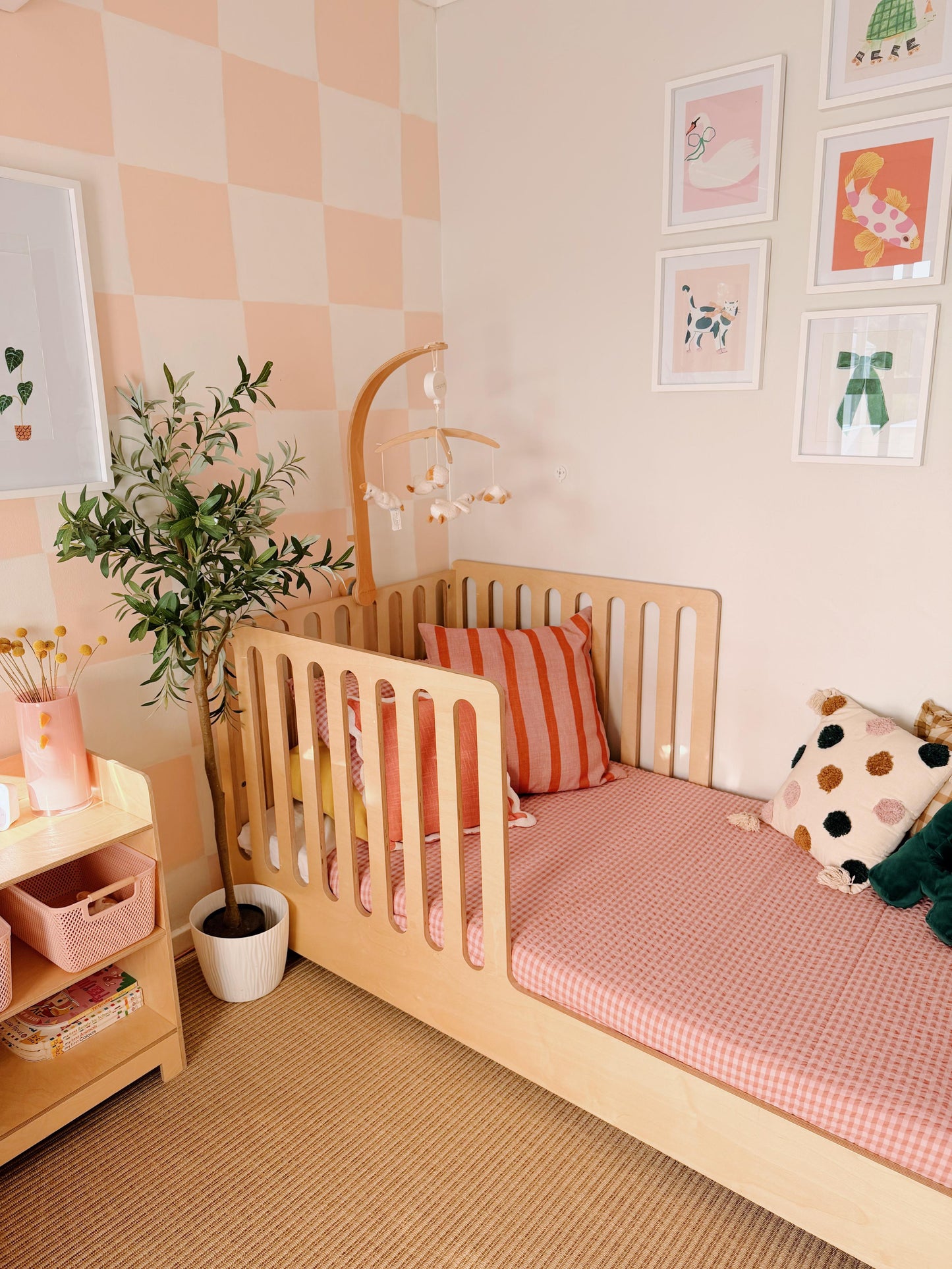 Children's room with a wooden crib, pink bedding, and decorative elements.