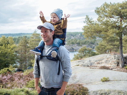 Parent carrying child using the MiniMeis G5 Shoulder Carrier during a nature hike