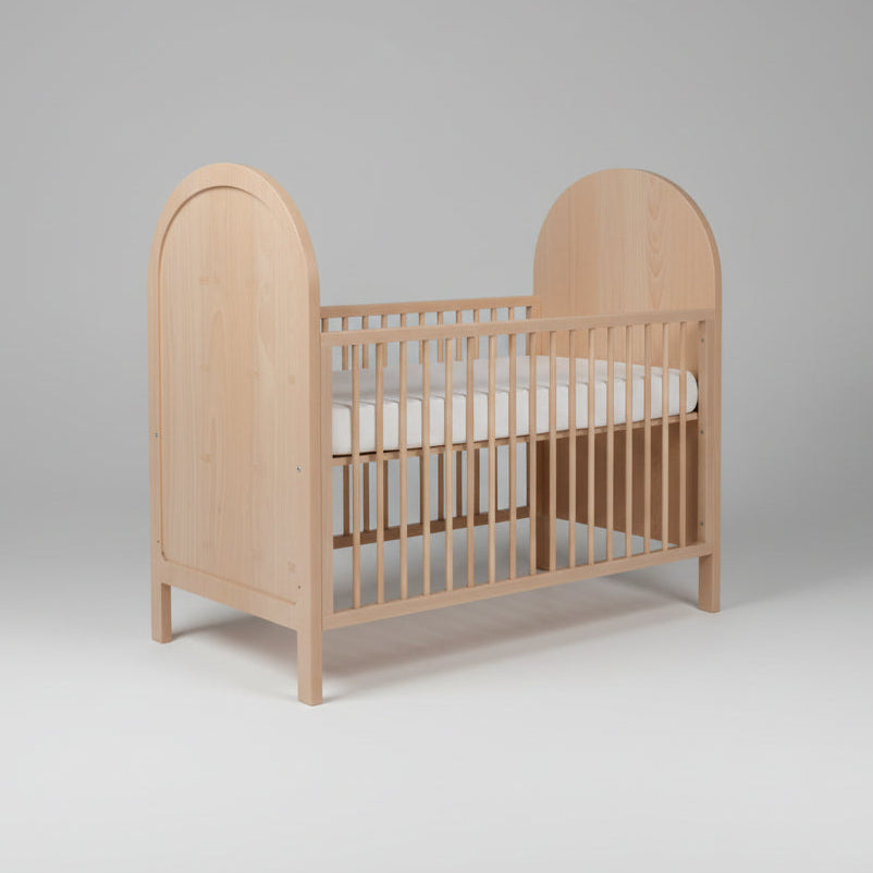 Wooden crib with a white mattress on a gray background