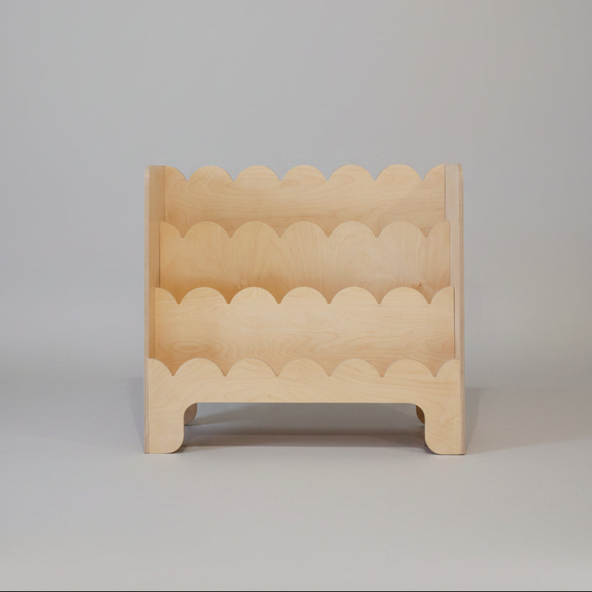 Wooden toddler book shelve with wavy edge design on a plain background