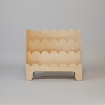Wooden toddler book shelve with wavy edge design on a plain background