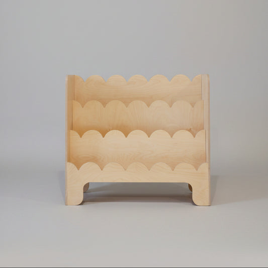 Wooden toddler book shelve with wavy edge design on a plain background