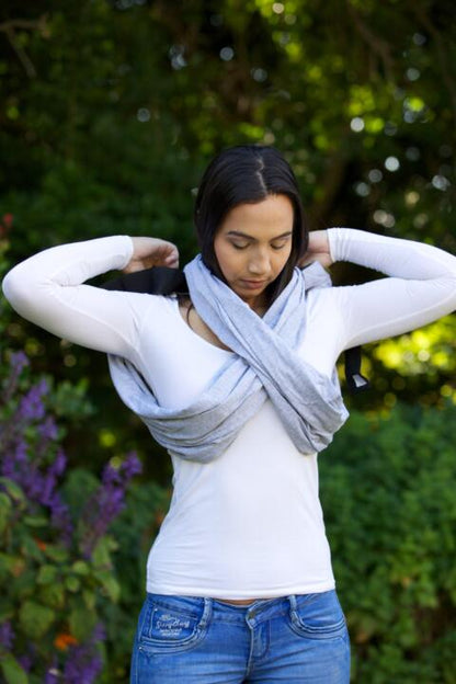 Parent wearing the SnuggleRoo Baby Carrier in the Newborn position, cradling a sleeping infant