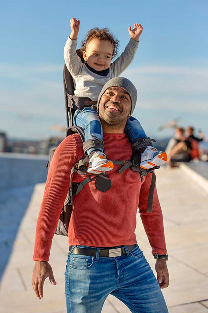 Parent carrying child using the MiniMeis G5 Shoulder Carrier during a nature hike
