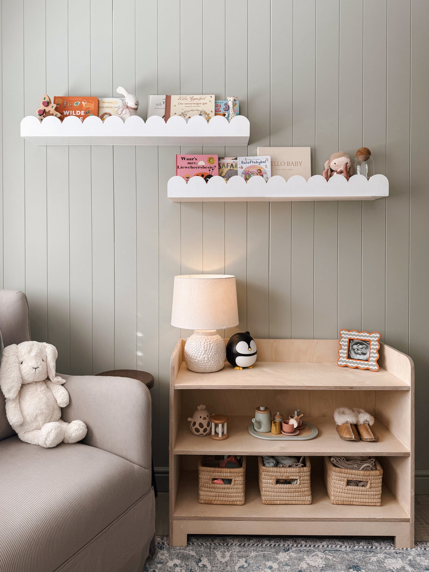 Nursery room with shelves, lamp, and toys against a gray wall.