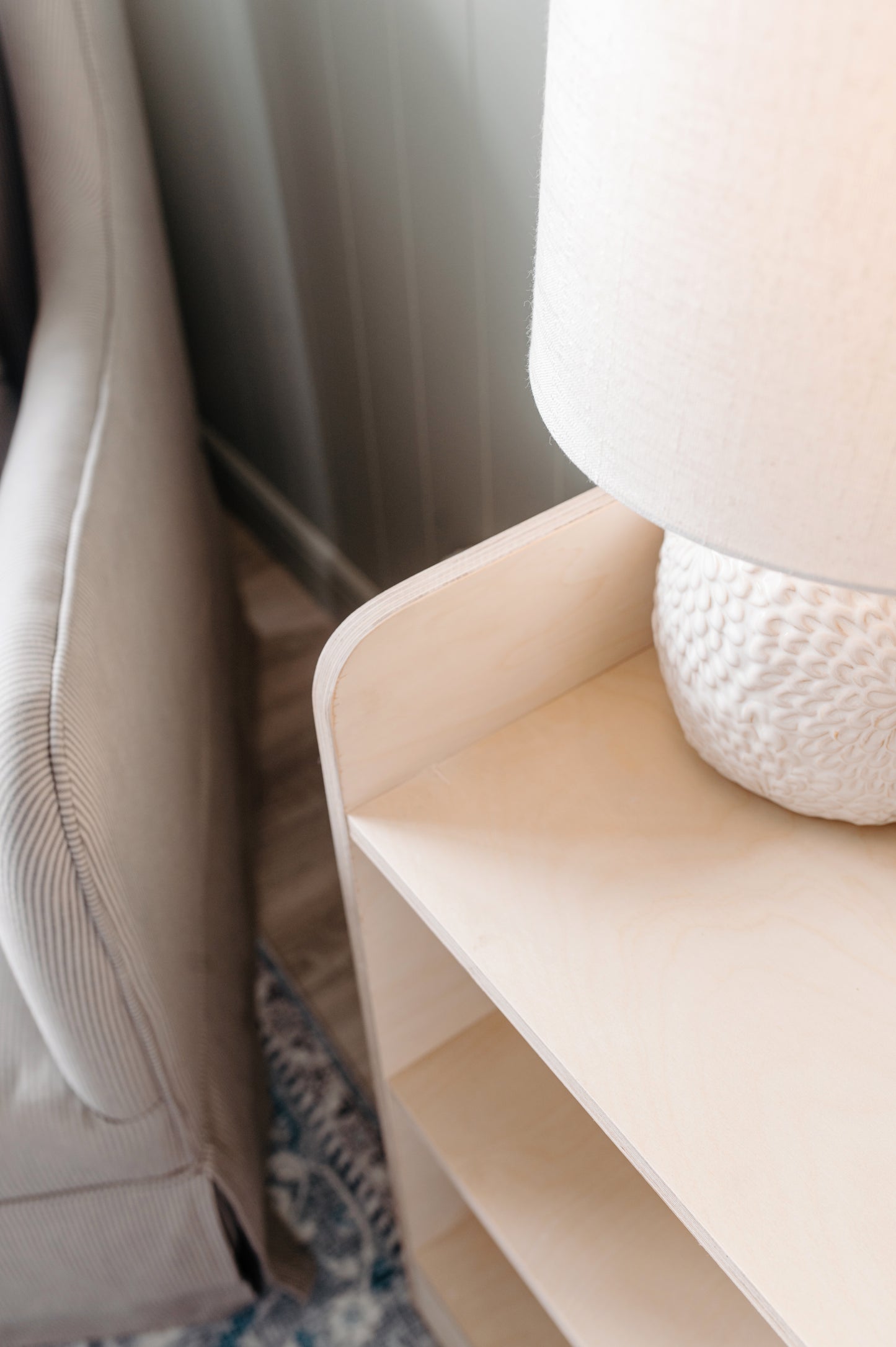 Beige corner shelf with a textured white lamp on a neutral background