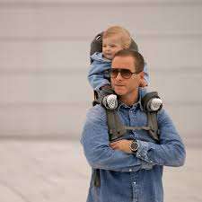 Parent carrying child using the MiniMeis G5 Shoulder Carrier during a nature hike