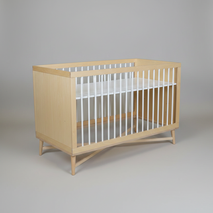 Wooden crib with white mattress on a plain background