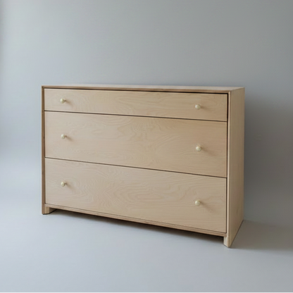 Wooden dresser with four drawers against a plain wall.