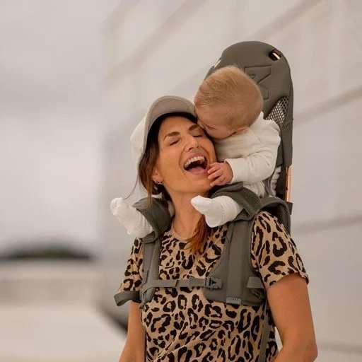 Happy child riding on parent's shoulders secured by the MiniMeis G5 Carrier