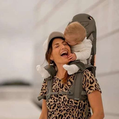 Happy child riding on parent's shoulders secured by the MiniMeis G5 Carrier
