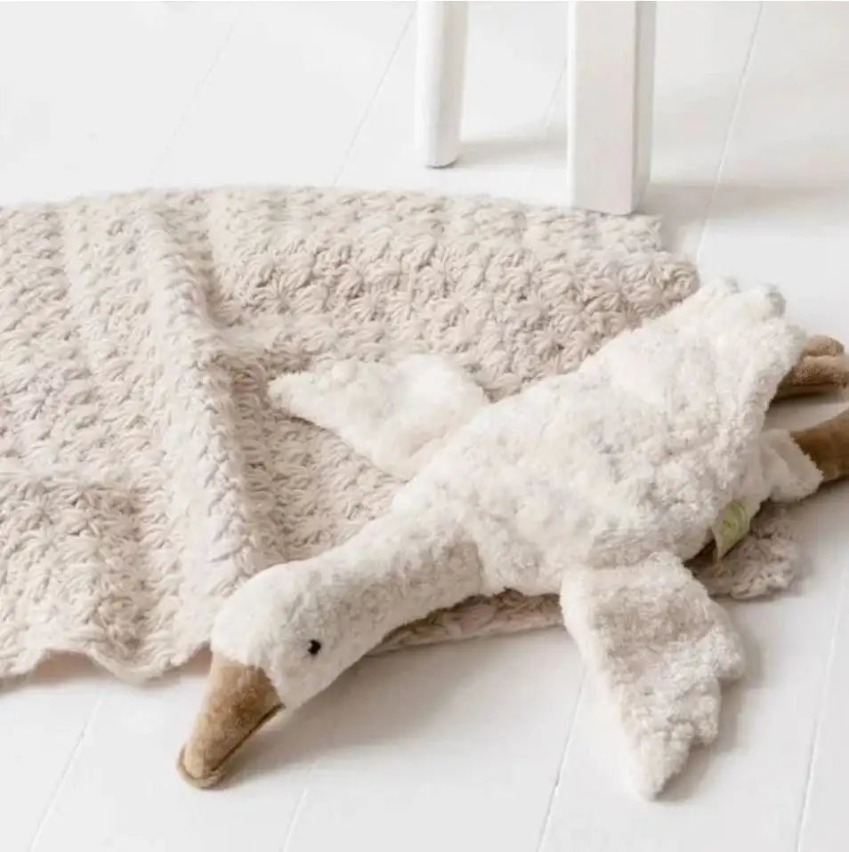 Snooz Gooz plush goose in light brown cuddling with baby blanket