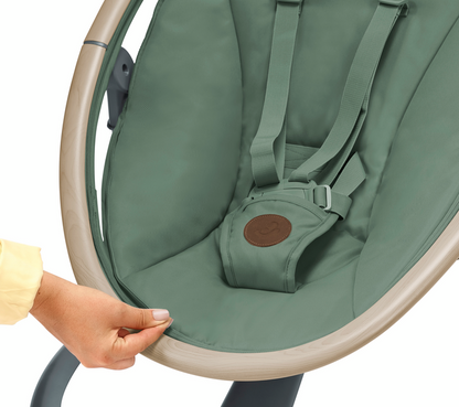 Green baby bouncer with a hand adjusting the straps on a white background